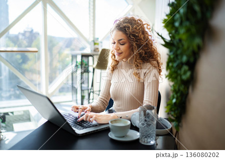 Young woman enjoying remote work in a coffee shop Young woman enjoying remote work in a coffee shop 136080202