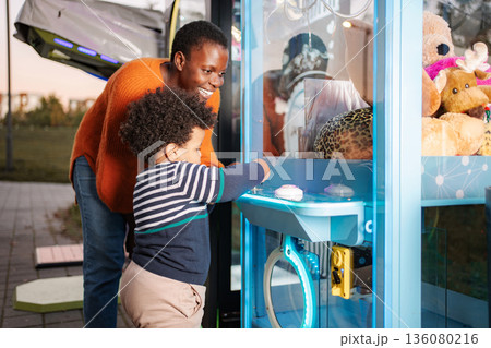 Mother son playing claw machine arcade game outdoors Mother son playing claw machine arcade game outdoors 136080216