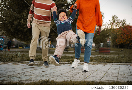 Parents swinging child playing outdoors in autumn park 136080225