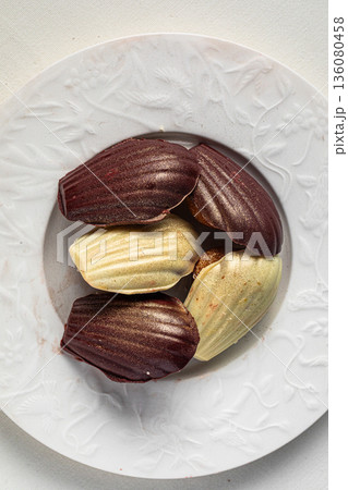 Assorted chocolate madeleine cakes on white plate Assorted chocolate madeleine cakes on white plate 136080458