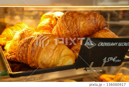 Freshly baked croissants displaying in a French bakery window, golden pastry inviting for a delicious breakfast or snack in Paris 136080917
