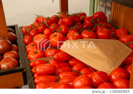 Fresh and ripe tomatoes displaying in a Parisian market stall with a brown paper bag for shopping Fresh and ripe tomatoes displaying in a Parisian market stall with a brown paper bag for shopping 136080985