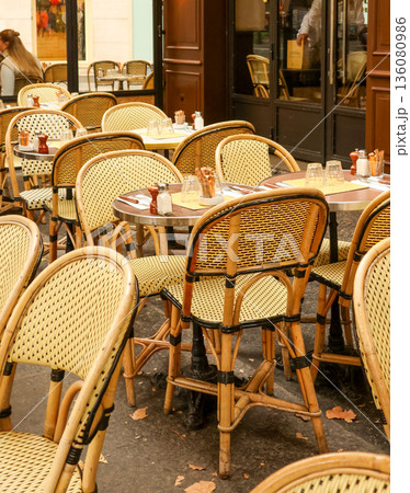 Paris cafe terrace with empty wicker chairs and small tables, inviting relaxation and dining al fresco in France 136080986