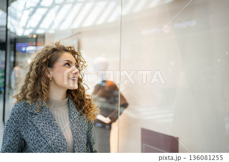 Young woman smiling enjoying window shopping at mall Young woman smiling enjoying window shopping at mall 136081255
