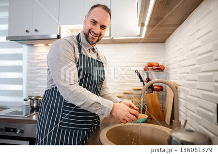 Man washing tomato in kitchen sink preparing food 136081379