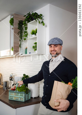 Smiling man carrying reusable box and bag with groceries home 136081392