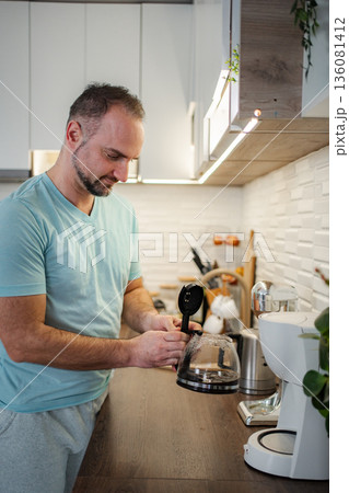 Man preparing morning coffee in a modern kitchen Man preparing morning coffee in a modern kitchen 136081412