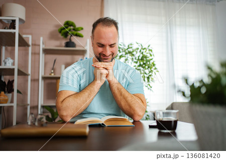 Mid adult man enjoying reading book at home Mid adult man enjoying reading book at home 136081420