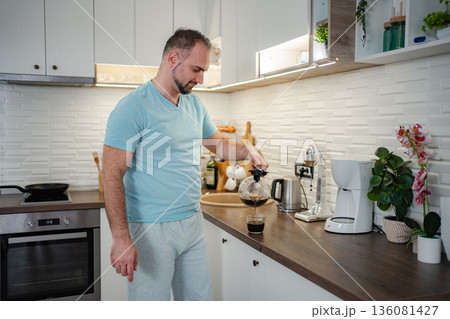 Man pouring fresh hot coffee in kitchen during morning routine 136081427
