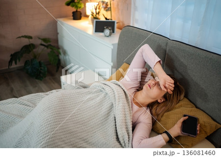 Woman having headache after sleepless night in bedroom Woman having headache after sleepless night in bedroom 136081460