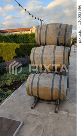 A collection of three elegantly stacked wooden barrels situated beautifully within a garden setting A collection of three elegantly stacked wooden barrels situated beautifully within a garden setting 136082666