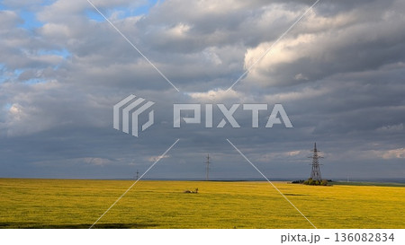 A Serene Landscape with Power Lines Under Dramatic Clouds in the Enchanting Sky Above 136082834