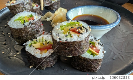 Savor delicious sushi rolls with soy sauce and colorful garnishes for a delightful experience Savor delicious sushi rolls with soy sauce and colorful garnishes for a delightful experience 136082838