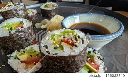 Indulge in these Delicious Sushi Rolls served with flavorful Soy Sauce and vibrant Garnishes Indulge in these Delicious Sushi Rolls served with flavorful Soy Sauce and vibrant Garnishes 136082840