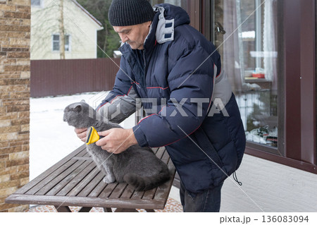 Senior male brushing pet outdoors near house highlighting daily routine compassion and calm interaction with animal. Senior male brushing pet outdoors near house highlighting daily routine compassion and calm interaction with animal. 136083094