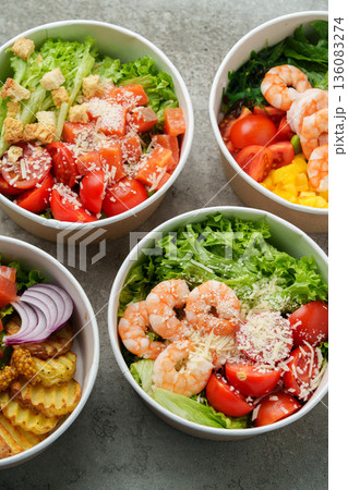 Fresh salads with shrimp and vegetables served in bowls on a gray surface 136083274