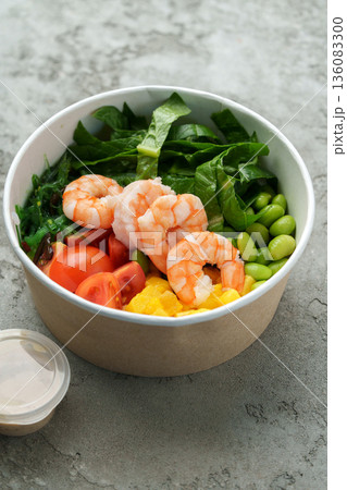 Shrimp salad with greens and tomatoes served in a bowl for lunch in a casual setting 136083300