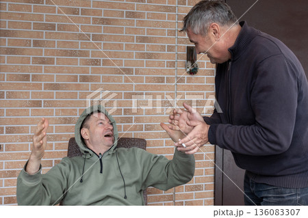 Two adult men arguing on outdoor wooden terrace near house expressing disagreement conflict and strong emotions. 136083307