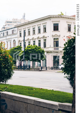 Building on the street corner with trees and cars in a city scene during the day Building on the street corner with trees and cars in a city scene during the day 136083335