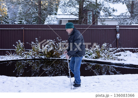Male person near water pond throwing food to fish on snow covered landscape. Peaceful lifestyle moment on natural light scene. Male person near water pond throwing food to fish on snow covered landscape. Peaceful lifestyle moment on natural light scene. 136083366