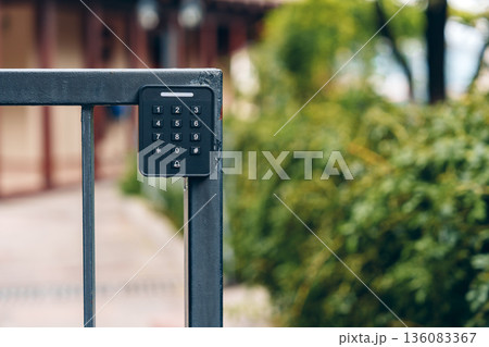 Keypad entry system near a gate in a garden area during daytime Keypad entry system near a gate in a garden area during daytime 136083367