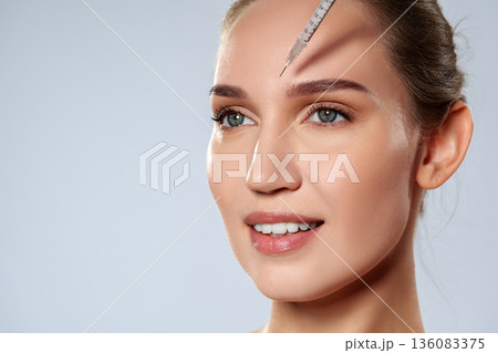 Woman receives treatment on her forehead in a clinic during the day in a light setting 136083375
