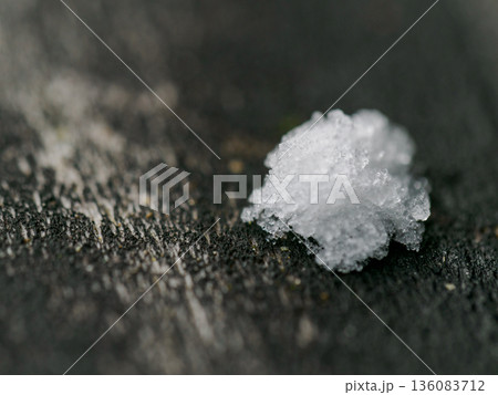 黒い木肌の上に一粒だけ残った結晶のような雪のマクロ撮影 黒い木肌の上に一粒だけ残った結晶のような雪のマクロ撮影 136083712