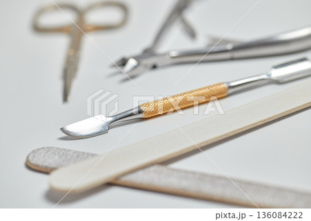 Manicure implements including a nail file, cuticle pusher, clippers, and scissors on a white background 136084222