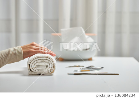 Woman enjoying a self-care beauty routine with a hand on a rolled white towel Woman enjoying a self-care beauty routine with a hand on a rolled white towel 136084234