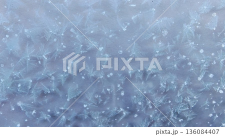 Purple Frost Crystals on Frozen Glass. Delicate Violet Frost Patterns on Window. Stunning macro frost patterns with fern-like ice crystals in violet-purple hues on cold window in winter. Purple Frost Crystals on Frozen Glass. Delicate Violet Frost Patterns on Window. Stunning macro frost patterns with fern-like ice crystals in violet-purple hues on cold window in winter. 136084407