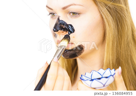 Girl being apply carbo mask to skin face Girl being apply carbo mask to skin face 136084955