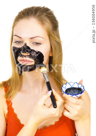 Woman being apply black mask to skin face Woman being apply black mask to skin face 136084956