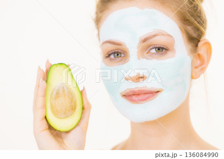 Girl facial mud mask holds avocado fruit Girl facial mud mask holds avocado fruit 136084990