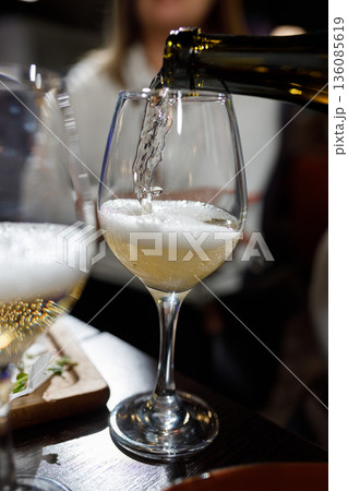 Pouring champagne into a glass at a celebration 136085619