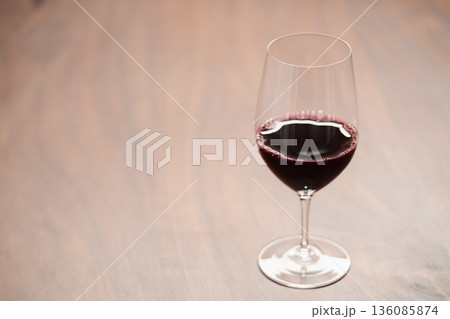 Red wine in wineglass on black walnut table with copy space Red wine in wineglass on black walnut table with copy space 136085874