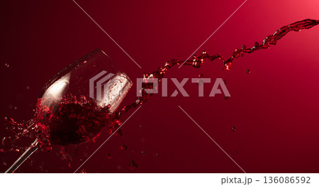 Glass and red wine splash on a dark red background. Glass and red wine splash on a dark red background. 136086592