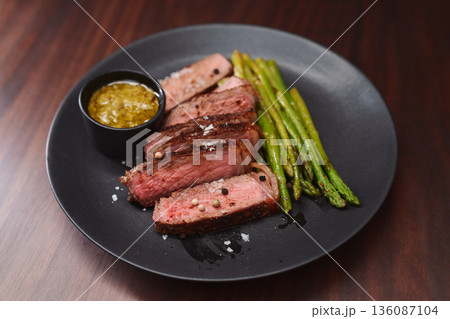 New york steak with asparagus on black plate with pesto New york steak with asparagus on black plate with pesto 136087104