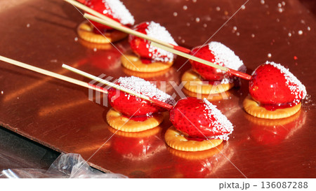 クラッカー付きの串に刺さったいちご飴 136087288