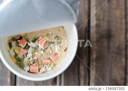 お湯を入れる前のシーフード味のカップラーメンの具と粉末スープ 136087302