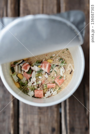 お湯を入れる前のシーフード味のカップラーメンの具と粉末スープ 136087303