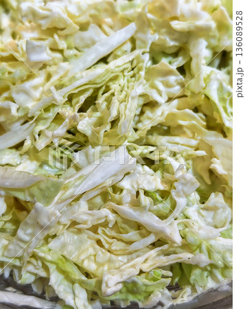 Fresh cabbage is chopped and ready for use in a coleslaw or salad dish. This shows the process of food preparation in a kitchen 136089528