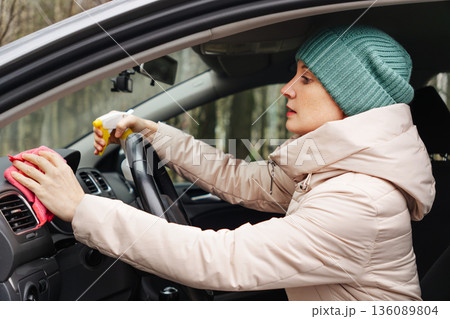 An adult woman is cleaning her car An adult woman is cleaning her car 136089804