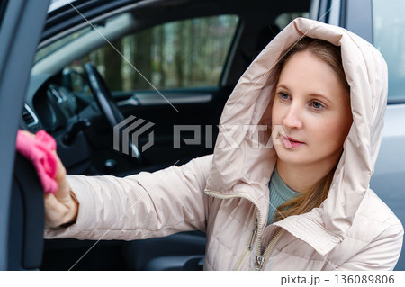 A young woman on the street is cleaning in her car A young woman on the street is cleaning in her car 136089806
