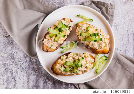 Close up of sandwiches with cod liver salad, egg and cucumber on a plate on the table top view 136089835