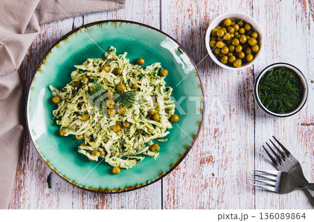 Green salad with cabbage, peas and dill on a plate on the table top view Green salad with cabbage, peas and dill on a plate on the table top view 136089864