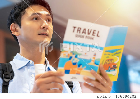 男性がガイドブックを読む ■撮影協力：関西国際空港（KIX） 136090282