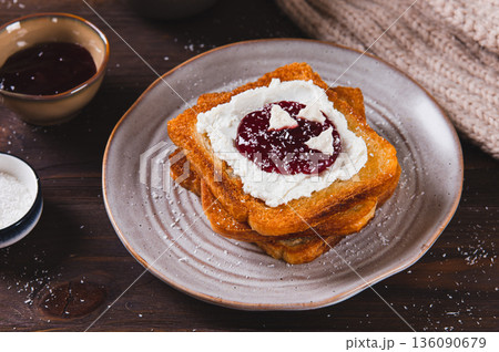 Delicious toasts with cream cheese, jam, paste and coconut flakes on a plate on the table 136090679