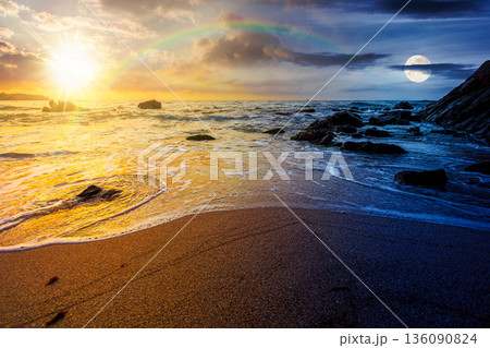 empty sandy beach at the sea. day and night time change concept. white foam rolling on to the shore near boulder with sun and moon at twilight. perfect summer vacation concept. astrology wallpaper 136090824
