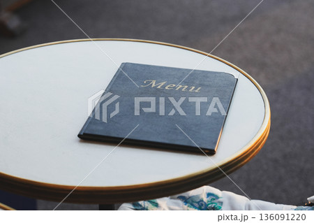 The black leather menu book on the table. 136091220