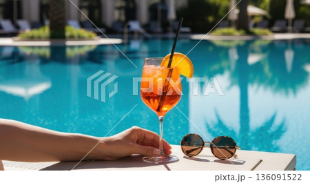 Vibrant Orange Spritz Cocktail on Poolside Table Under Clear Sky 136091522